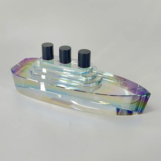 Iridescent glass object with three black cylindrical elements on a white background