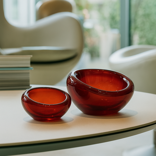 Two red glass bowls on a light-colored surface with a blurred indoor background